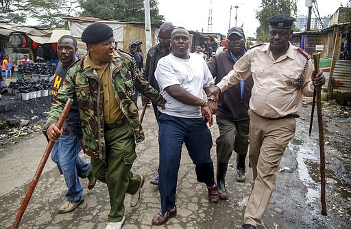 Security forces arrest a man for operating a restaurant serving food to customers eating on the premises, which has been prohibited and only takeaways are allowed under measures aimed at halting the spread of the new coronavirus, in Nairobi, Kenya Friday, March 27, 2020. The new coronavirus causes mild or moderate symptoms for most people, but for some, especially older adults and people with existing health problems, it can cause more severe illness or death. (AP Photo/Brian Inganga)