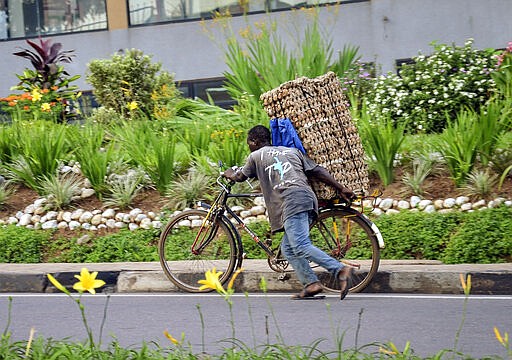 In this photo taken Thursday, March 26, 2020 a man transports cartons of eggs on the back of a bicycle due to restrictions on movement attempting to halt the spread of the new coronavirus, in Kigali, Rwanda. The new coronavirus causes mild or moderate symptoms for most people, but for some, especially older adults and people with existing health problems, it can cause more severe illness or death. (AP Photo)