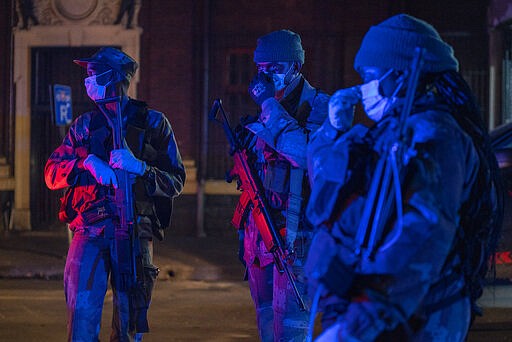 Lit by police lights, South African Defense Forces patrol downtown Johannesburg, South Africa, Friday, March 27, 2020. Police and army started patrolling moments after South Africa went into a nationwide lockdown for three weeks in an effort to mitigate the spread to the coronavirus. The new coronavirus causes mild or moderate symptoms for most people, but for some, especially older adults and people with existing health problems, it can cause more severe illness or death.(AP Photo/Jerome Delay)