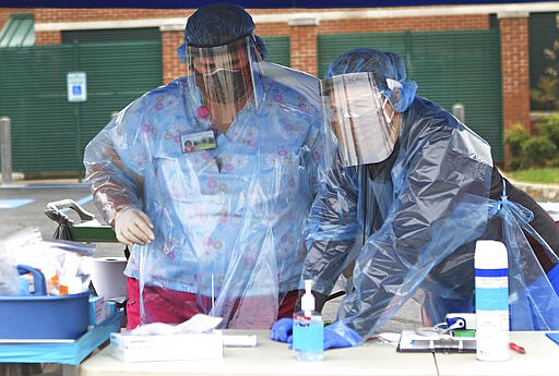 Nurses Teresa Adkins, left, and Hope Ridgeway work at a Mobile Health Unit for drive-thru coronavirus testing at Robert C. Byrd Clinic on the campus of the West Virginia School of Osteopathic Medicine in Lewisburg, W.Va., Tuesday, March 24, 2020. The nurses and doctors can test for COVID-19, but also treat flu and allergy symptoms.   (Jenny Harnish/The Register-Herald via AP)