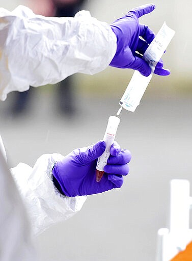 A clinical care providers collects a swab for coronavirus during drive-thru testing by the Fayette County Health Department in Oak Hill , W.V. on Thursday, March 19, 2020. (Chris Jackson/The Register-Herald via AP)