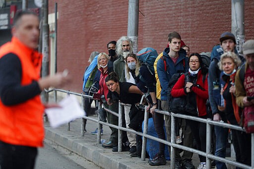 Stranded German tourists wait for a bus to take them to the airport in Kathmandu, Nepal, Friday, March 27, 2020. A rescue flight arranged by the German government on Friday picked up tourists who had been stranded in Nepal since the Himalayan nation went on lockdown earlier this week, officials said. The airport reopened only for the flight, which did not bring any passengers to Nepal. Up to 10,000 tourists are believed to be stranded in Nepal since the government ordered a complete lockdown that halted all flights and road travel to prevent the spread of the virus. (AP Photo/Niranjan Shrestha)