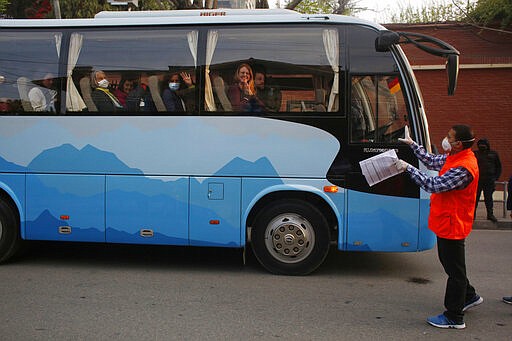 Stranded German wave to journalists as they prepare to move to the airport in Kathmandu, Nepal, Friday, March 27, 2020. A rescue flight arranged by the German government on Friday picked up tourists who had been stranded in Nepal since the Himalayan nation went on lockdown earlier this week, officials said. The airport reopened only for the flight, which did not bring any passengers to Nepal. Up to 10,000 tourists are believed to be stranded in Nepal since the government ordered a complete lockdown that halted all flights and road travel to prevent the spread of the virus. (AP Photo/Niranjan Shrestha)