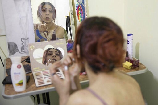 In this Feb. 18, 2020 photo, Egyptian transgender woman and activist Malak el-Kashif puts on makeup in her bedroom, in Cairo, Egypt. El-Kashif punctuates her recounting of painful life events with jokes and sarcastic comments. As she talks, she smokes heavily, fidgets or plays with her hair--which she had colored red and often wears a lipstick shade to match. (AP Photo/Nariman El-Mofty)