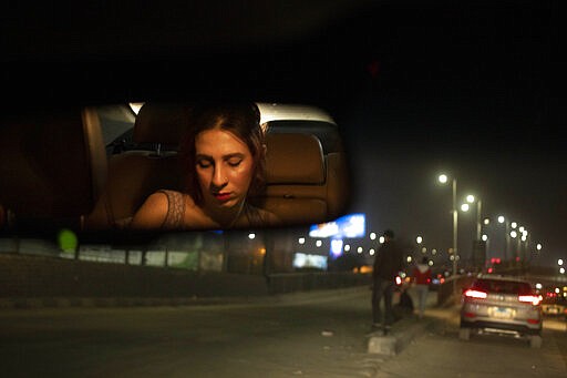 In this Feb. 20, 2020 photo, transgender woman and activist Malak el-Kashif, reflected in the rear view mirror of a car, looks at her mobile phone, in Cairo, Egypt. Shortly before her birthday last year, el-Kashif posted a picture of herself online writing that she had completed her gender transitioning surgeries. One mother approached her at a hospital and said she sought medical help for her daughter after hearing el-Kashif's story. Another time, a transgender man stopped her to let her know that &quot;To me, you are resistance.&quot; (AP Photo/Nariman El-Mofty)