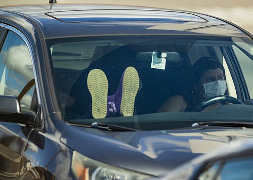 FILE - In this Wednesday, March 25, 2020, file photo, unidentified Los Angeles residents wait in their vehicles lined outside the Crenshaw Christian Center before it opens as testing site for the new coronavirus in South Los Angeles. (AP Photo/Damian Dovarganes)