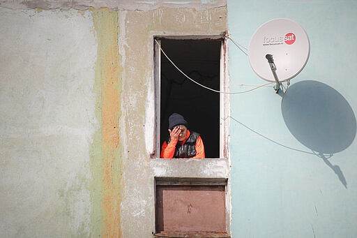 An elderly woman stands in a window in a poor area of Bucharest, Romania, Friday, March 27, 2020 as authorities try to limit the spread of the new coronavirus, one of the measures being forbidding people over 65 years of age to leave their homes, except for a two hour interval. The new coronavirus causes mild or moderate symptoms for most people, but for some, especially older adults and people with existing health problems, it can cause more severe illness or death. (AP Photo/Vadim Ghirda)