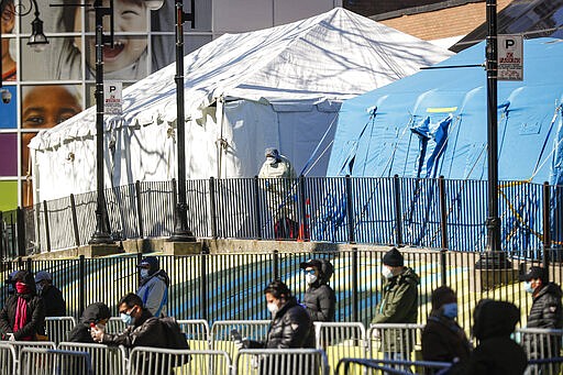 A medical worker looks out onto a line of patients waiting for COVID-19 testing outside Elmhurst Hospital Center, Friday, March 27, 2020, in New York. The new coronavirus causes mild or moderate symptoms for most people, but for some, especially older adults and people with existing health problems, it can cause more severe illness or death. (AP Photo/John Minchillo)