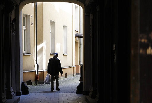 An elderly man returns home with his shopping, which is one of the very few outdoor activities allowed under a national quarantine against the spread of the coronavirus, in Warsaw, Poland, on Thursday, March 26, 2020. The new coronavirus causes mild or moderate symptoms for most people, but for some, especially older adults and people with existing health problems, it can cause more severe illness or death.(AP Photo/Czarek Sokolowski)