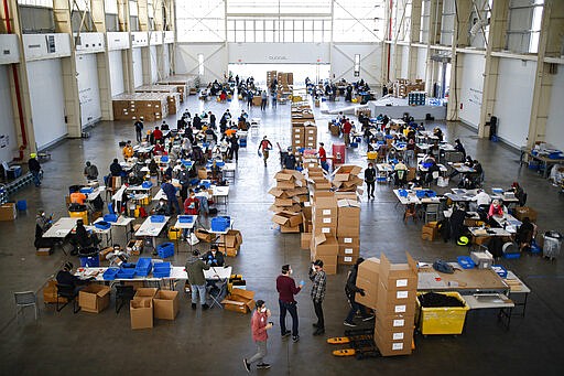 Workers, wearing personal protective equipment, build splash guards during a mass manufacturing operation to supply New York City government with protection to distribute against COVID-19, Friday, March 27, 2020, at the Brooklyn Navy Yard in New York. The new coronavirus causes mild or moderate symptoms for most people, but for some, especially older adults and people with existing health problems, it can cause more severe illness or death. (AP Photo/John Minchillo)