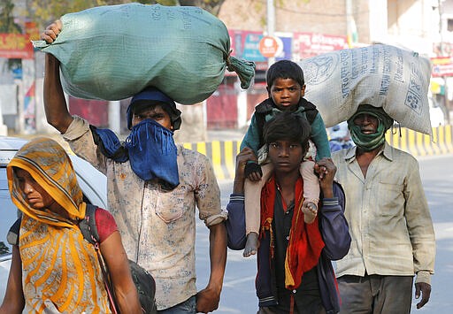 A group of daily wage laborers walk to return to their villages as the city comes under lockdown in Prayagraj, India, Friday, March 27, 2020. Some of India's legions of poor and others suddenly thrown out of work by a nationwide stay-at-home order began receiving aid on Thursday, as both public and private groups worked to blunt the impact of efforts to curb the coronavirus pandemic. The measures that went into effect Wednesday, the largest of their kind in the world, risk heaping further hardship on the quarter of the population who live below the poverty line and the 1.8 million who are homeless. (AP Photo/Rajesh Kumar Singh)