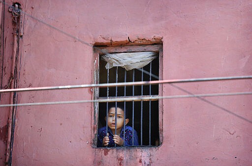 A child looks out from the window of his house in the old quarters of Delhi following a lockdown amid concern over spread of coronavirus, India, Friday, March 27, 2020. Some of India's legions of poor and others suddenly thrown out of work by a nationwide stay-at-home order began receiving aid on Thursday, as both public and private groups worked to blunt the impact of efforts to curb the coronavirus pandemic. The measures that went into effect Wednesday, the largest of their kind in the world, risk heaping further hardship on the quarter of the population who live below the poverty line and the 1.8 million who are homeless. (AP Photo/Manish Swarup)