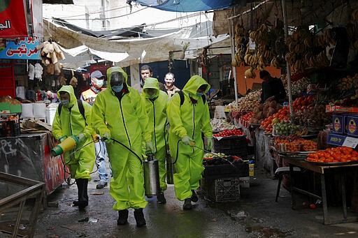 Workers wearing protective gear spray disinfectant as a precaution against the coronavirus, at the main market in Gaza City, Friday, March 27, 2020. Gaza municipality close all the weekly Friday markets in Gaza starting from today. (AP Photo/Adel Hana)