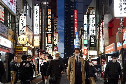 People make their way along a street of Tokyo's Shinjuku district, Friday, March 27, 2020. Tokyo governor on Wednesday requested the city's 1.3 million residents to stay home this weekend, saying Japanese capital city is on the verge of explosive COVID-19 infections. (AP Photo/Jae C. Hong)