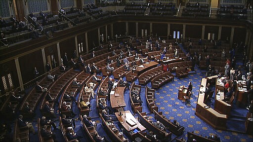 In this image from video, members of the House practice social distancing as they sit on the floor and in the public gallery above during debate on the coronavirus stimulus package on the floor of the House of Representatives at the U.S. Capitol in Washington, Friday, March 27, 2020. (House Television via AP)