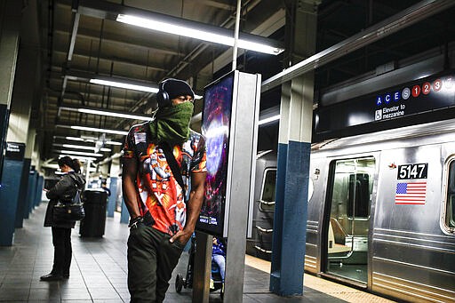 FILE - In this March 20, 2020, file photo, a subway customer walks a sparsely populated 42nd Street Times Square platform while covering his face due to coronavirus concerns in New York. Los Angeles is half the size of New York City but has a disproportionately small fraction of the coronavirus cases and deaths as the nation's largest city. The same goes for California when compared with New York state as a whole, which is the current epicenter of the outbreak in the U.S. (AP Photo/John Minchillo, File)