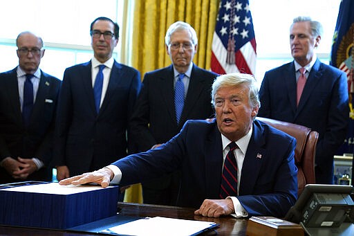 President Donald Trump speaks before he signs the coronavirus stimulus relief package in the Oval Office at the White House, Friday, March 27, 2020, in Washington. Listening are from left, Larry Kudlow, White House chief economic adviser, Treasury Secretary Steven Mnuchin, Senate Majority Leader Mitch McConnell, R-Ky., and House Minority Leader Kevin McCarty of Calif. (AP Photo/Evan Vucci)