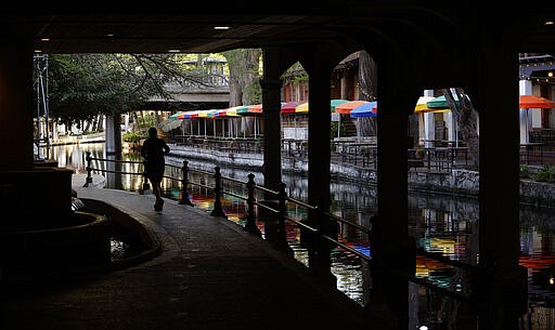 FILE - In this March 24, 2020, file photo, a runner moves along a mostly deserted River Walk in San Antonio, where most restaurants and business are closed. (AP Photo/Eric Gay, File)