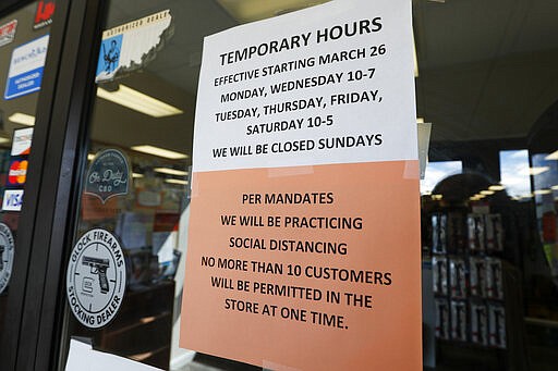 Signs on the front doors of Dukes Sport Shop show the hours and conditions to comply with conditions to reopen Wednesday, March 25, 2020, after being closed by last week's ordered shut down of non-essential businesses by Pennsylvania Gov. Tom Wolf, in New Castle, Pa. (AP Photo/Keith Srakocic)