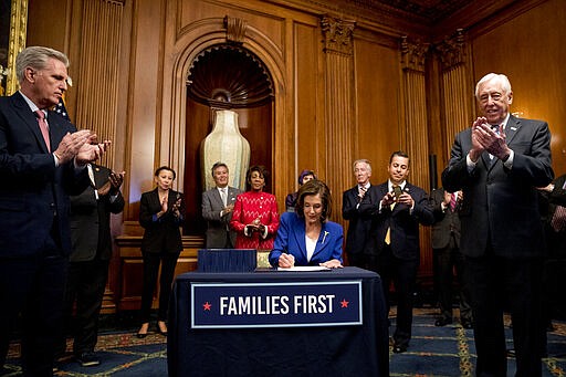 House Speaker Nancy Pelosi of Calif., accompanied by House Minority Leader Kevin McCarthy of Calif., left, House Majority Leader Steny Hoyer of Md., right, and other bipartisan legislators, signs the Coronavirus Aid, Relief, and Economic Security (CARES) Act after it passed in the House on Capitol Hill, Friday, March 27, 2020, in Washington. The $2.2 trillion package will head to head to President Donald Trump for his signature. (AP Photo/Andrew Harnik)