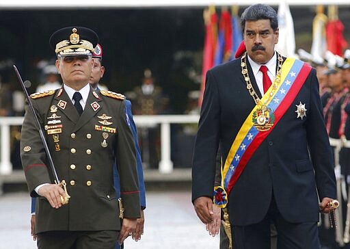 FILE - In this May 24, 2018 file photo, Venezuela's President Nicolas Maduro, right, walks with his Defense Minister Vladimir Padrino Lopez as they review the troops during a military parade at Fort Tiuna in Caracas, Venezuela. On Thursday, March 26, 2020, the U.S. Justice Department made public it has charged in several indictments against Maduro and his inner circle, including Padrino, that the leader has effectively converted Venezuela into a criminal enterprise at the service of drug traffickers and terrorist groups as he and his allies stole billions from the South American country. (AP Photo/Ariana Cubillos, File)