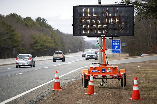 A sign instructs motorists with New York license plates to pull over at a checkpoint on I-95 over the border from Connecticut where New Yorkers must pull over and provide contact information and are told to self-quarantine for two weeks, Saturday, March 28, 2020, in Hope Valley, R.I. Rhode Island Gov. Gina Raimondo on Saturday ordered anyone visiting the state to self-quarantine for 14 days and restricted residents to stay at home and nonessential retail businesses to close Monday until April 13 to help stop the spread of the coronavirus. (AP Photo/David Goldman)