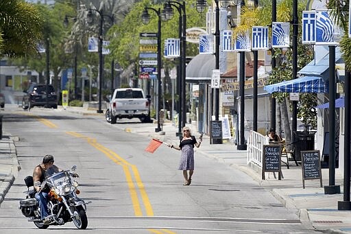 Terry Bruillard steps into Dodecanese Boulevard to encourage people to visit Yianni's Greek Restaurant, which remains open Friday, March 27, 2020, at the Tarpon Springs (Fla.) Sponge Docks, which remain mostly empty since Pinellas County issued a &quot;Safer at Home&quot; order in the wake of the acceleration cases of the coronavirus in Florida. (Douglas R. CliffordTampa Bay Times via AP)