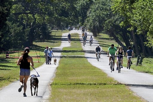 Runners, walkers and cyclists enjoy a section of the Pinellas Trail north of downtown Dunedin, Fla., Friday, March 27, 2020. (Douglas R. Clifford/Tampa Bay Times via AP)