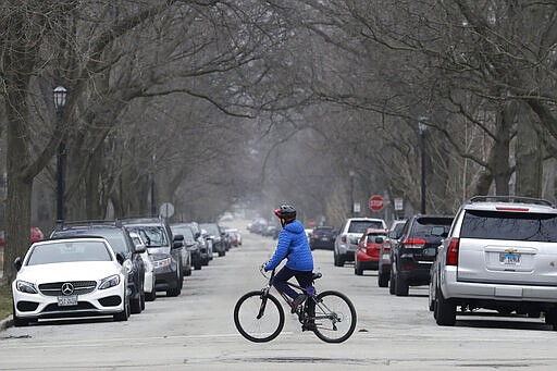 A resident rides his bicycle on the street in Evanston, Ill., Friday, March 27, 2020. Lack of social distancing in Chicago led to the closure of parks and trails amid COVID-19 outbreak. (AP Photo/Nam Y. Huh)