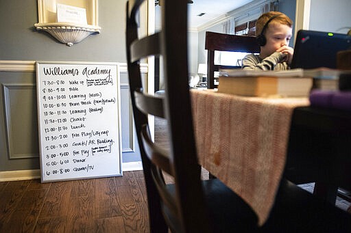 A board displays the Williams family's schedule as the children work on projects at home Friday, March 20, 2020 in Decatur, Ala. Emily Williams, their mother, is a third grade teacher at Austinville Elementary. (Dan Busey/The Decatur Daily via AP)