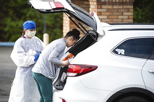 A woman delivers medical supplies at a screening clinic at Hartselle Family Practice, organized by Decatur Morgan Hospital, on Tuesday, March 24, 2020, in Hartselle, Ala. Those who meet the criteria for COVID-19 testing are sent to another site. (Dan Busey/The Decatur Daily via AP)