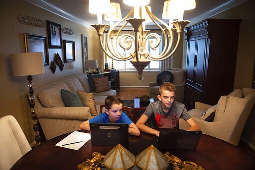 Brothers John Evan, 9, left, an elementary student, and Mason Sinclair, 12, a middle school student, extend their learning with virtual projects on their Chromebooks at their home on Friday, March 20, 2020, in Decatur, Ala. (Dan Busey/The Decatur Daily via AP)