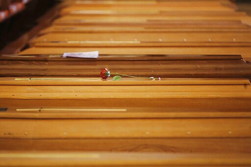 A red rose lies on a coffin lined up along others inside the San Giuseppe church in Seriate, Italy, to be blessed before being sent to crematoriums in Udine and Venice, Northern Italy, Saturday, March 28, 2020. The new coronavirus causes mild or moderate symptoms for most people, but for some, especially older adults and people with existing health problems, it can cause more severe illness or death. (AP Photo/Antonio Calanni)