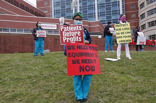 Nurses stand on a hill outside the emergency entrance to Jacobi Medical Center in the Bronx borough of New York, Saturday, March 28, 2020, as they demonstrate with members of the New York Nursing Association in support of obtaining an adequate supply of personal protective equipment for those treating coronavirus patients. A member of the New York nursing community died earlier in the week at another New York hospital. The city leads the nation in the number of coronavirus cases. Nurses say they are having to reuse their protective equipment endangering patients and themselves. (AP Photo/Kathy Willens)