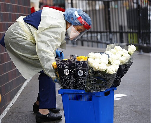 An emergency room nurse transports a bucket of donated flowers up a ramp leading to the ER outside Elmhurst Hospital Center in New York, Saturday, March 28, 2020. The hospital has been heavily taxed recently treating an influx of coronavirus patients. Currently New York leads the nation in the number of cases, according to Johns Hopkins University, which is keeping a running tally. (AP Photo/Kathy Willens)