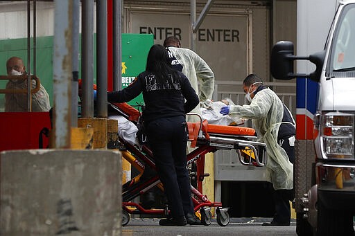 An elderly patient is wheeled into the emergency entrance to Elmhurst Hospital Center in New York, Saturday, March 28, 2020.  The hospital is caring for a high number of coronavirus patients in the city.   (AP Photo/Kathy Willens)