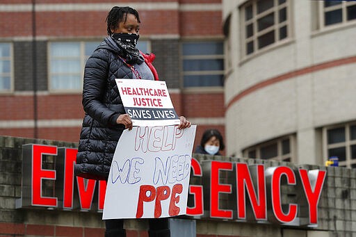 A nurse stands outside the emergency entrance to Jacobi Medical Center in the Bronx borough of New York, Saturday, March 28, 2020, as she demonstrates with members of the New York Nursing Association in support of obtaining an adequate supply of personal protective equipment for nurses coming in contact with coronavirus patients. A member of the New York nursing community died earlier in the week at another New York hospital. The city leads the nation in the number of coronavirus cases. Nurses say they are having to reuse their equipment endangering patients and themselves. (AP Photo/Kathy Willens)