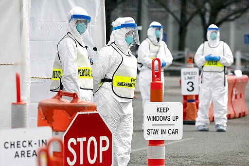 Medical personnel wait to screen people arriving at a special COVID-19 testing site in Boston, Saturday, March 28, 2020. The drive-thru testing site is only open to qualified first responders who meet the state criteria for testing. The new coronavirus causes mild or moderate symptoms for most people, but for some, especially older adults and people with existing health problems, it can cause more severe illness or death. (AP Photo/Michael Dwyer)