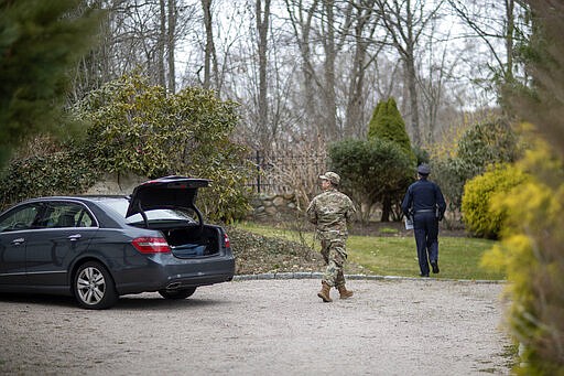 Rhode Island Air National Guard Tsgt. William Randall, left, and Westerly police officer Howard Mills approach a home while looking for New York license plates in driveways to inform them of self quarantine orders, Saturday, March 28, 2020, in Westerly, R.I. States are pulling back the welcome mat for travelers from the New York area, which is the epicenter of the country's coronavirus outbreak, and some say at least one state's measures are unconstitutional. Gov. Gina Raimondo ratcheted up the measures announcing she ordered the state National Guard to go door-to-door in coastal communities starting this weekend to find out whether any of the home's residents have recently arrived from New York and inform them of the quarantine order. (AP Photo/David Goldman)