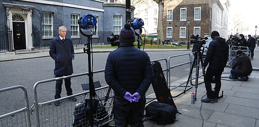 Journalists keep their distance as they report from Downing Street in London after it was announced that British Prime Minister Boris Johnson has tested positive for the new coronavirus, Friday, March 27, 2020. Johnson's office said Friday that he was tested after showing mild symptoms, Downing Street says Johnson is self-isolating and continuing to lead the country's response to COVID-19. (AP Photo/Frank Augstein)