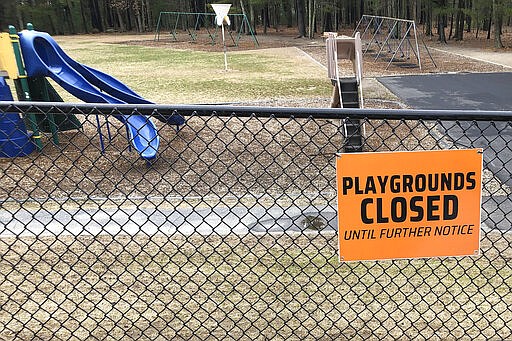 FILE - This Friday, March 20, 2020 file photo shows a closed sign near an entrance to a playground at an elementary school in Walpole, Mass., amid the COVID-19 coronavirus outbreak. Child welfare agencies in the U.S. have a difficult mission in the best of times, and now they're scrambling to confront new challenges during the coronavirus outbreak. (AP Photo/Steven Senne)