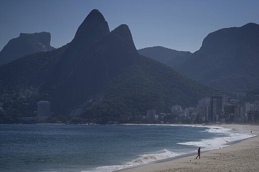 A man walks along the shore of an empty Ipanema beach in Rio de Janeiro, Brazil, Thursday, March 26, 2020, as many people stay home to help contain the spread of the new coronavirus. (AP Photo/Leo Correa)