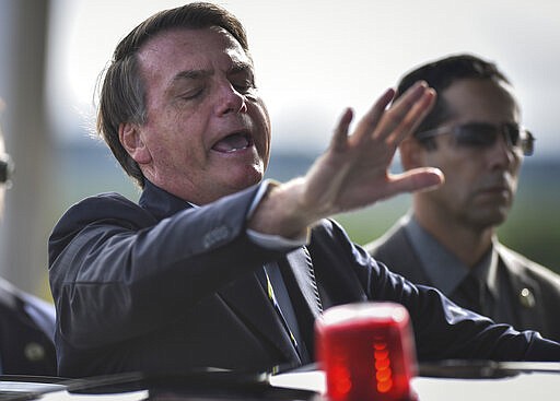 Brazil's President Jair Bolsonaro greets supporters and journalists as he arrives to give a news conference on the new coronavirus at Planalto presidential palace in Brasilia, Brazil, Friday, March 27, 2020. Even as coronavirus cases mount in Latin America&#146;s largest nation, Bolsonaro is calling the pandemic a momentary, minor problem and saying strong measures to contain it are unnecessary. (AP Photo/Andre Borges)