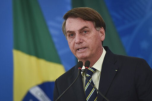 Brazil's President Jair Bolsonaro speaks to journalists about the new coronavirus at Planalto presidential palace in Brasilia, Brazil, Friday, March 27, 2020. Even as the new coronavirus cases mount in Latin America&#146;s largest nation, Bolsonaro is calling the pandemic a momentary, minor problem and saying strong measures to contain it are unnecessary. (AP Photo/Andre Borges)