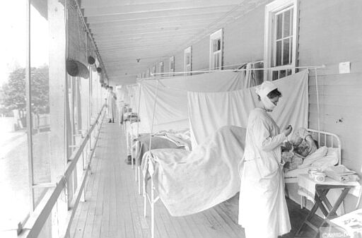 FILE - In this November 1918 photo made available by the Library of Congress, a nurse takes the pulse of a patient in the influenza ward of the Walter Reed hospital in Washington. For President Woodrow Wilson, the pandemic was a case of first impression. The country was accustomed to 100,000 deaths a year from the flu. Widespread use of vaccines were not common. It wasn't that Wilson was restrained about using federal power, he simply had far less precedent to lean on, and a much higher priority in the war effort.  (Harris &amp; Ewing/Library of Congress via AP, File)