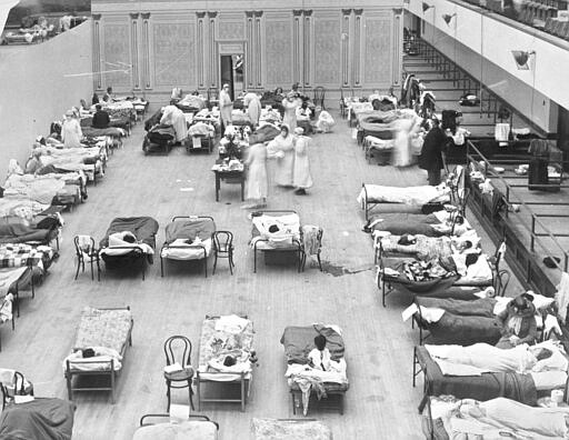 FILE - In this 1918 file photo made available by the Library of Congress, volunteer nurses from the American Red Cross tend to influenza patients in the Oakland Municipal Auditorium, used as a temporary hospital. Woodrow Wilson did not address the nation on the subject of the pandemic of 1918-19 a single time, he did not call for Congress to act and he did not summon the nation to come together. (Edward A. &quot;Doc&quot; Rogers/Library of Congress via AP, File)