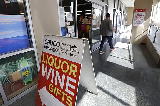 In this photo taken Wednesday, March 25, 2020, a shopper leaves a liquor store in Seattle. Many, if not most, liquor stores in Washington state are considered &quot;essential businesses&quot; and can stay open under Gov. Jay Inslee's stay-at-home order issued Monday in the midst of the coronavirus outbreak. (AP Photo/Elaine Thompson)