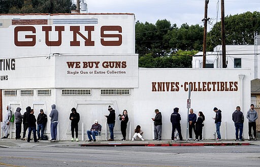 FILE - In this March 15, 2020, file photo, people wait in a line to enter a gun store in Culver City, Calif. The coronavirus pandemic has much of the world contemplating an existential question amid a growing number of stay-at-home orders, with only &quot;essential&quot; service providers allowed to go to their jobs. As U.S. states enact sweeping stay-at-home orders, there is lots of agreement on what's essential, but some have their own notions. A few are eyebrow raisers. Among them are guns, golf and cannabis. Most lists, being compiled by governors and others, capture the basics of what's essential. (AP Photo/Ringo H.W. Chiu, File)