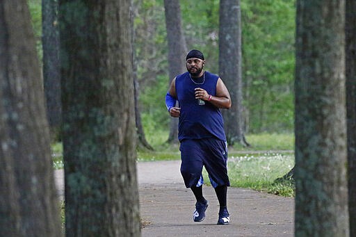 Jelani Houseworth, 41, runs along the 1-mile Parham Bridges walking track, Monday, March 23, 2020, in Jackson, Miss. Runners across the country are still hitting the pavement and the trails, staying fit and working off some stress amid the coronavirus pandemic.  (AP Photo/Rogelio V. Solis)