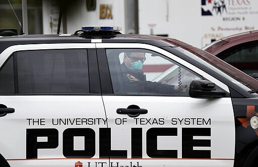 A police officer wears a mask as he speaks to a man at the check point for a coronavirus drive-thru test facility, Monday, March 16, 2020, in San Antonio.  According to the World  Health Organization, most people recover in about two to six weeks, depending on the severity of the illness.  (AP Photo/Eric Gay)